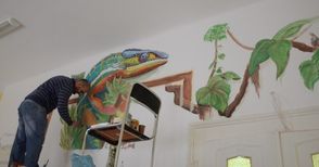 Шарен хамелеон пълзи по стената в Детския отдел на библиотеката