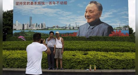 Китайци се снимат на фона на билборд с Дън Сяопин - най-важния лидер в новата история на страната.