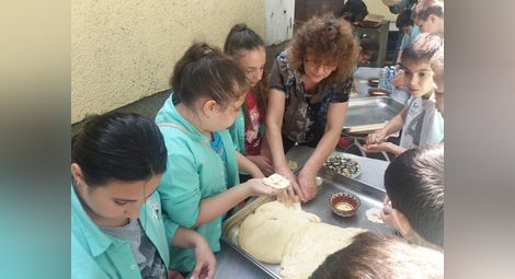 Учителката по труд и творчество Милена Тодорова помага на ученици да омесят питки.  Снимка:Утро