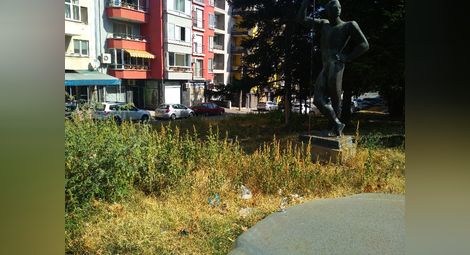 Паметникът на атлета до Градския аранжиран с дебела трева и трънаци