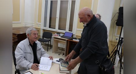 Среща на стари приятели - Руденко Йорданов взема автограф от Стефан Цанев.                               Снимка: РБ „Любен Каравелов“.