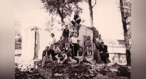 Директорът Никола Попниколов (седнал, трети отляво на втория ред) с учители и служители от Основно училище, Поликрайще, при разчистване на терена за строителство на политехническата работилница и спортната зала в двора на училището, 1961 г.