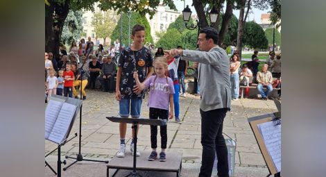 Маестро Димитър Косев дава уроци на ентусиазирани малки „колеги“, които един ден може да застанат на диригентския пулт също като нето. 		            Снимка: Държавна опера-Русе